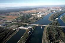 Ottmarsheim : vue aérienne de l’aménagement hydroélectrique sur le Grand Canal d’Alsace avec la centrale à gauche, le chenal de sortie de l’écluse au centre et la Rhin à droite
